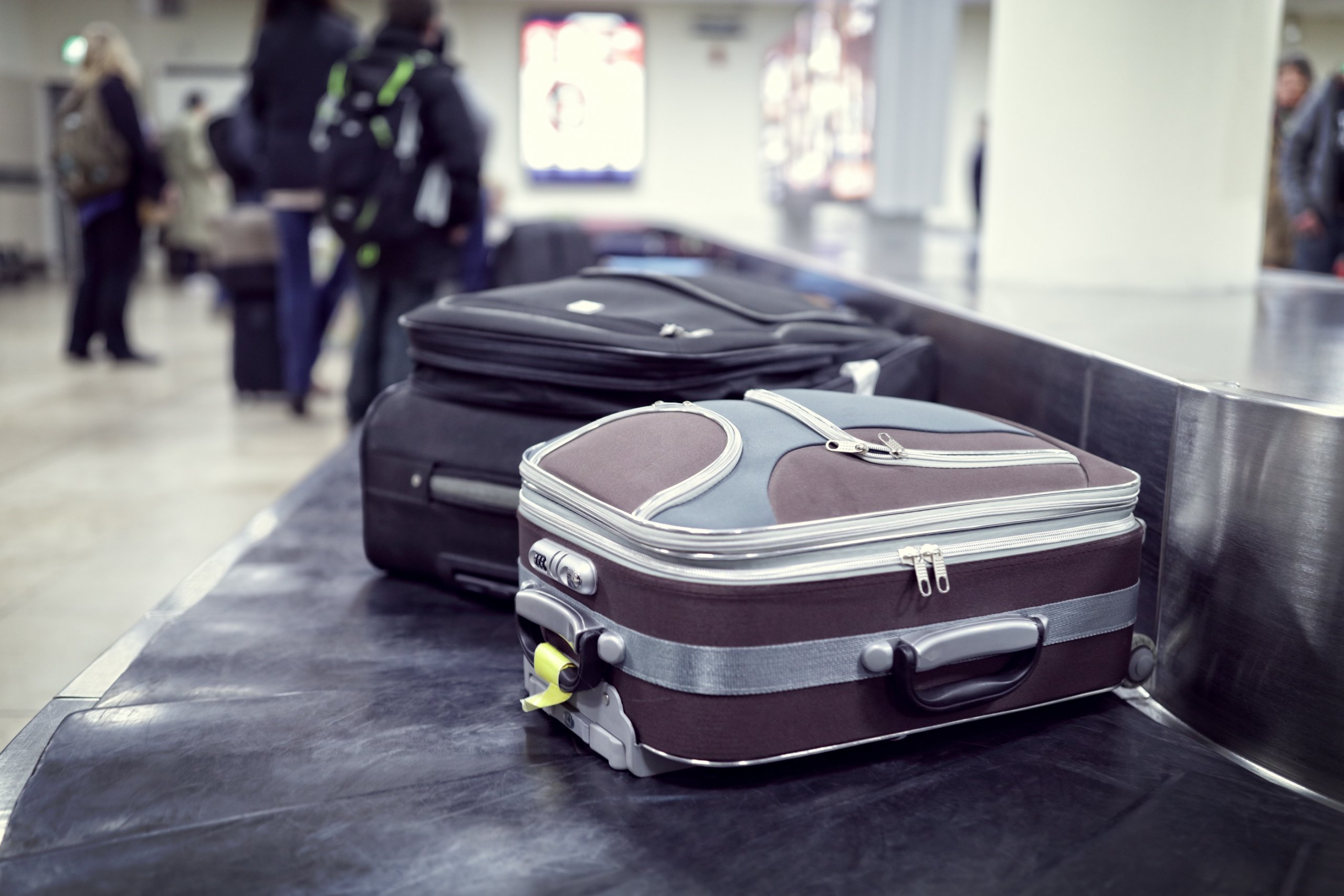 picture of suitcases at baggage claim, and using your Amex Airline Fee Credit can cover checked bag fees