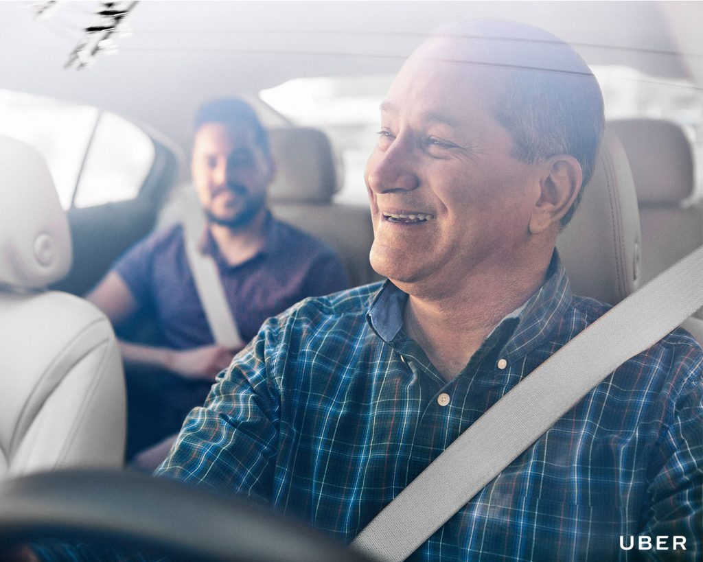 Uber driver smiles at rider through rearview mirror