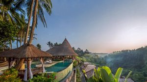 grass-thatched huts at a luxury hotel overlooking a jungle valley below