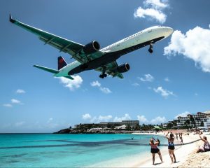 a Delta plane seen coming in for a landing over a beach with tourists on it