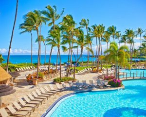 the pool surrounded by lounge chairs and palm trees at the Hilton Waikoloa Village in Hawaii