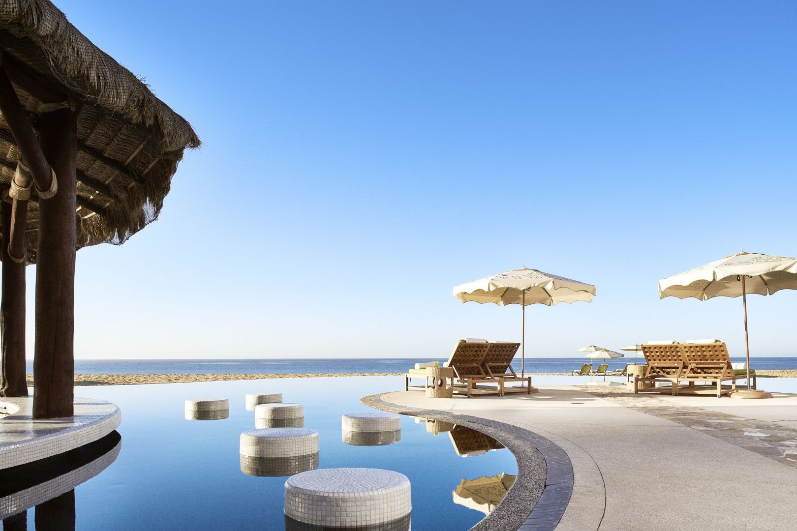 the pool and lounge chairs overlooking the ocean at Waldorf Astoria Los Cabos