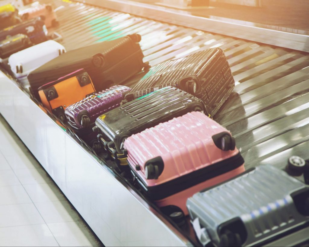 Several suitcases sit on the conveyor belt in the baggage claim area.