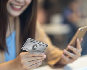 Image of woman holding an American Express Platinum Card and a mobile phone
