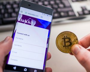 Image shows someone holding a phone with the Bakkt app on it, plus holding a symbol for bitcoin, since you can use these to cash out your Choice points