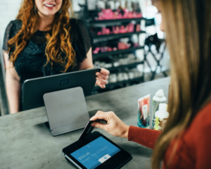 a woman inserts a credit card into a card reader to pay at a store