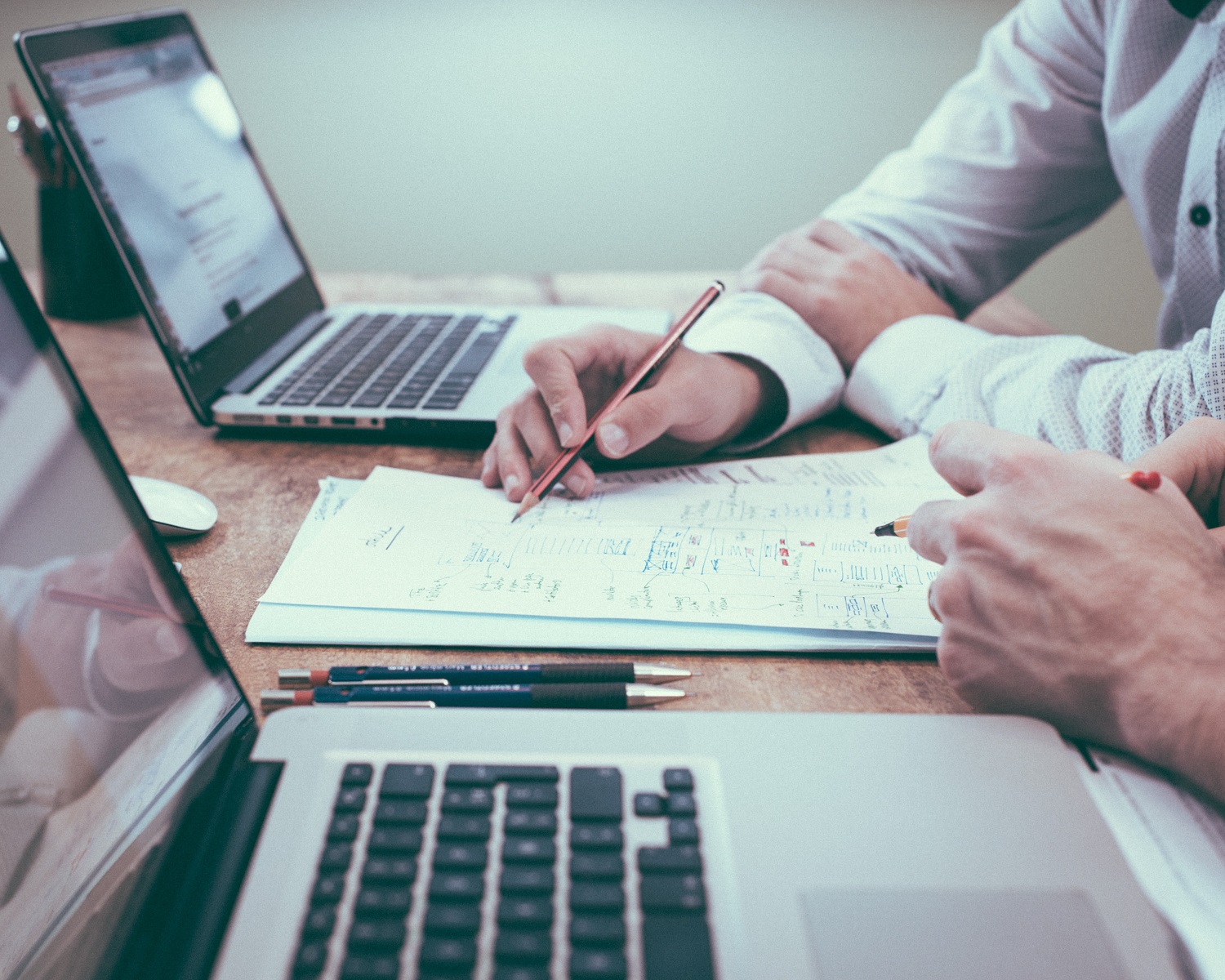 people look at documents and use laptops at a desk