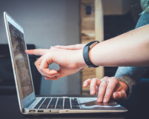 hands point at a laptop screen