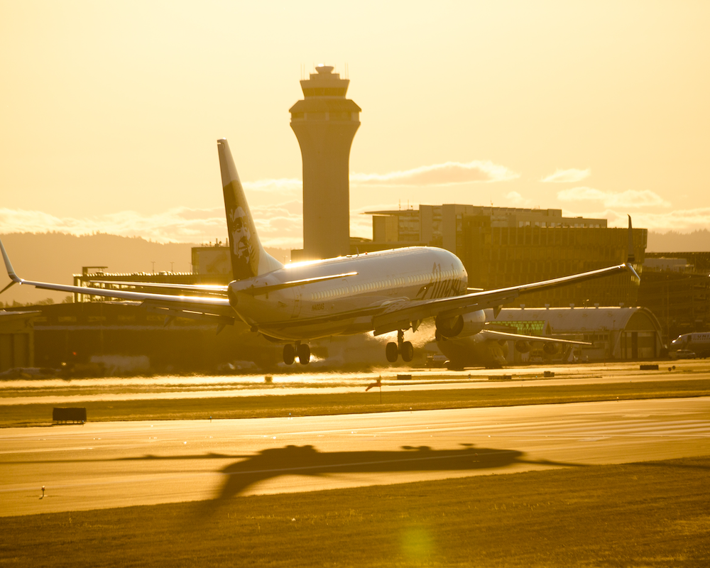 an Alaska Airlines plane lands at sunset