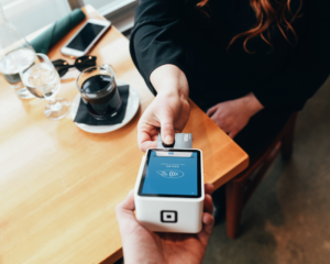 overhead view of a person at a café putting a credit card into a pay terminal