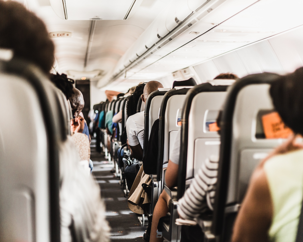 looking up the aisle toward the front of a plane, showing all seats are full in the economy section