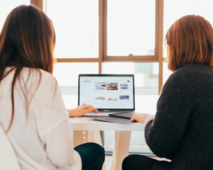 2 people look at a computer together while shopping online