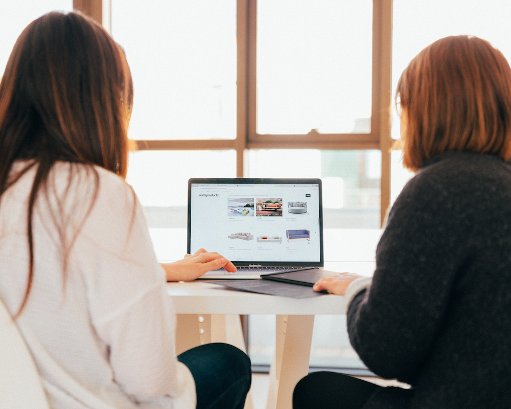 Two people look at a computer together while shopping online