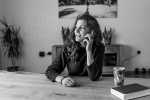 a woman sits at a kitchen table while making a phone call