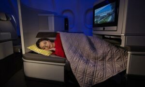 A woman sleeps in a lie-flat TAP Portugal business-class seat, which you can book for 35,000 miles through airline sweet spots.