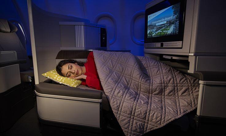 a woman sleeps in a lie-flat business-class seat