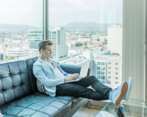 a man sits on a sofa using a laptop