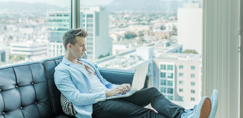 a man sits on a sofa using a laptop