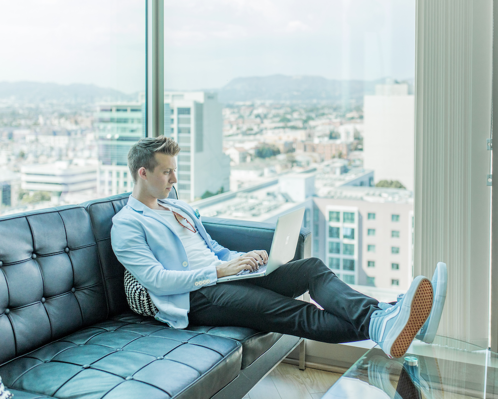 a man sits on a sofa using a laptop