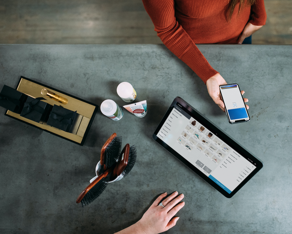 overhead view of a person paying by mobile wallet at a cash register; some credit cards offer an instant card number that you can use with mobile wallets before your physical card arrives