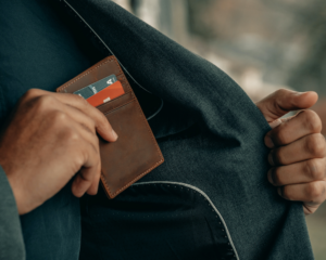 an unseen person puts a wallet into their jacket pocket