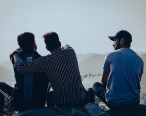 friends sit together on a hilltop