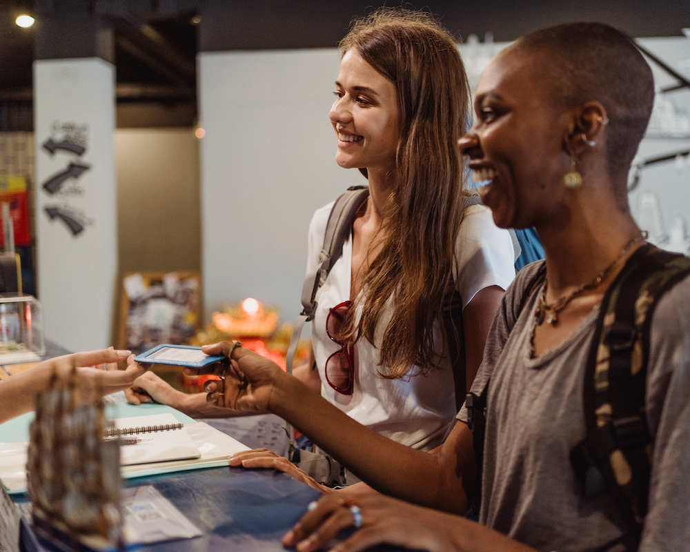 2 friends pay with a credit card at a hotel front desk