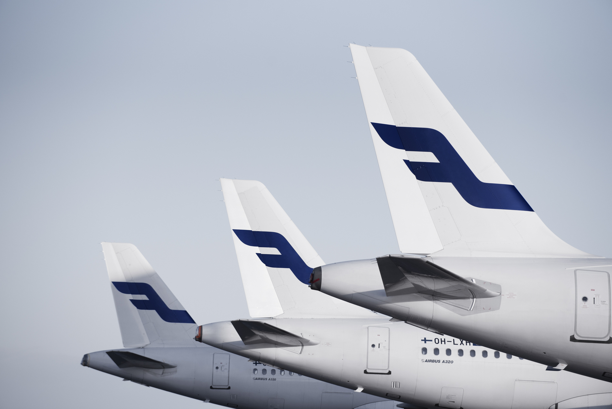 3 Finnair aircraft lined up on the ramp at an airport.