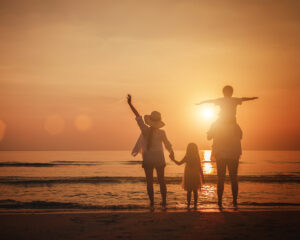 Summer vacation, Happy family together on the beach in holiday. Silhouette of the family holding hands enjoying the sunset on the tropical beach.