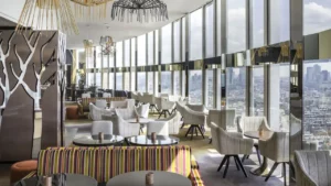 restaurant tables and white chairs with floor-to-ceiling glass windows overlooking paris
