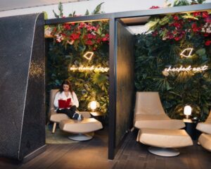 a traveler relaxes on a lounge chair surrounded by plants and candles in a chic airport lounge