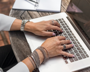hands from an unseen person typing on a laptop keyboard