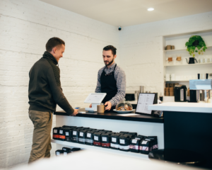 a person pays by credit card at a local coffee shop