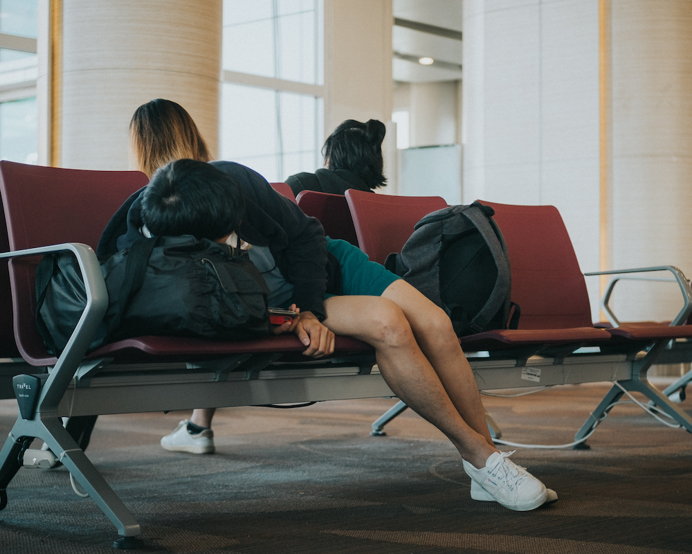 a passenger sleeps on a row of seats during a flight delay