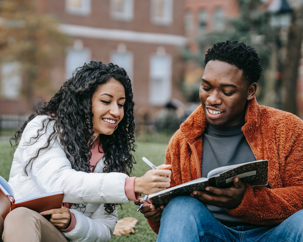 2 university students study together on the lawn