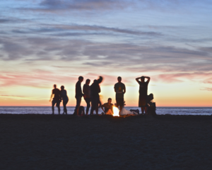 friends have a fire on the beach at sunset