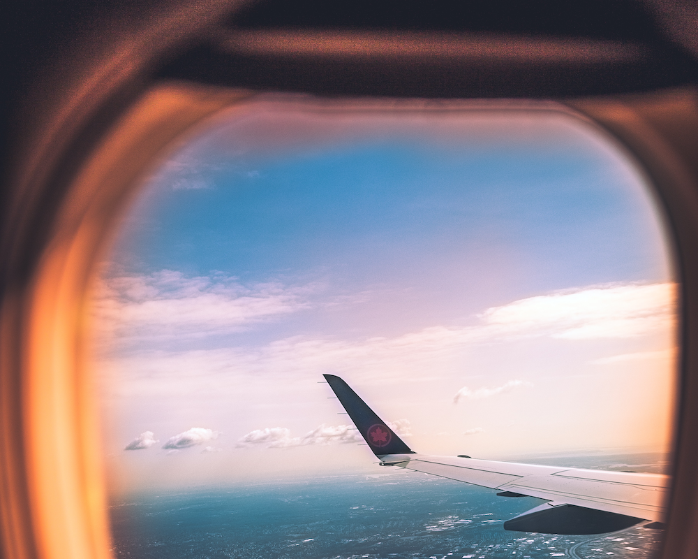 looking out a plane window at an Air Canada logo on the wingtips