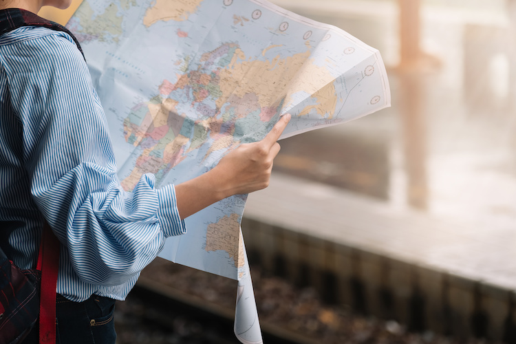 Shot of a young woman traveler or backpacker using map choose where to travel at train, Travel Concept