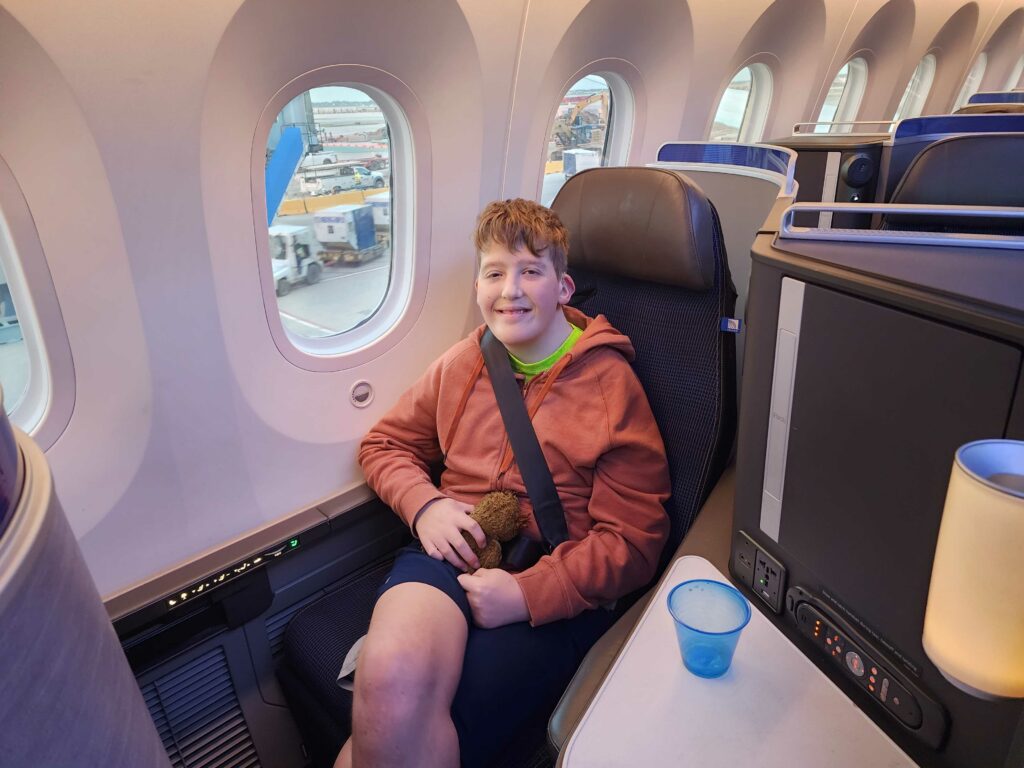 a teenager sits in a business class seat on a plane