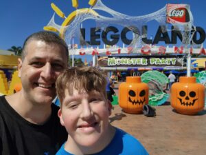 A father and son in front of the Legoland sign