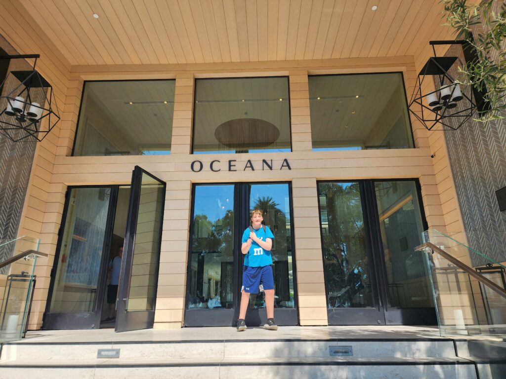 a teenager stands in front of the Oceana hotel entrance