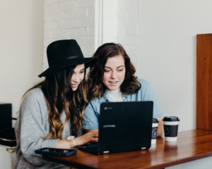 2 friends use a laptop together to consider getting the Citi Simplicity Card