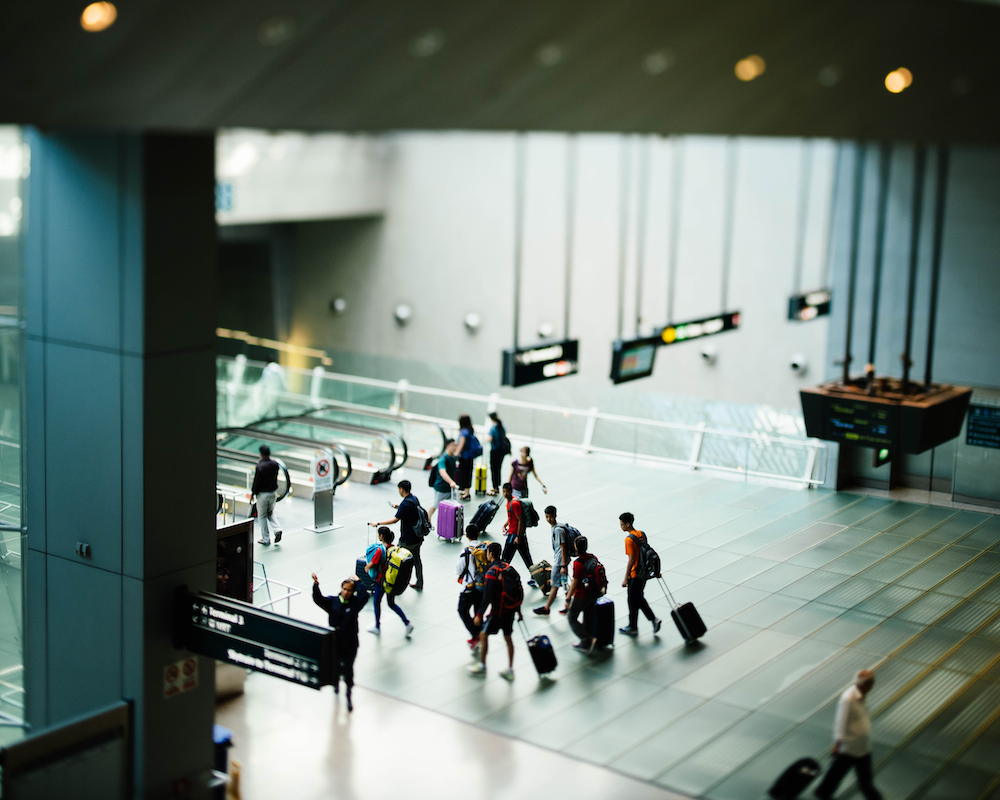 numerous passengers move through an airport with their luggage