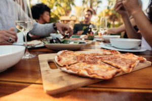 Friends enjoy pizza and salad around a table.