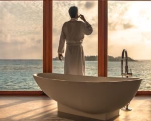 a man in a bathroom looks out the window of his luxury hotel room