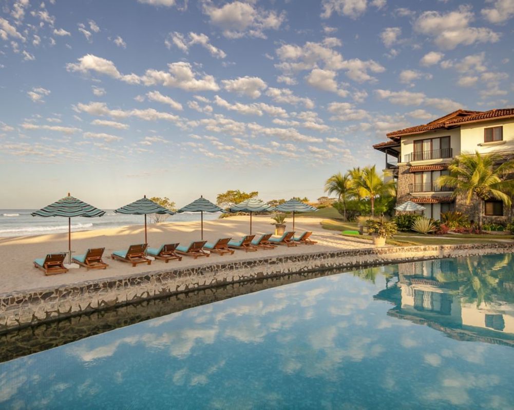 a Spanish colonial-style luxury hotel with pool and beach