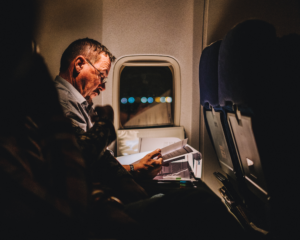a plane passenger reads documents using the overhead light during a night-time flight