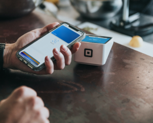 an unseen person taps their phone to pay by mobile wallet