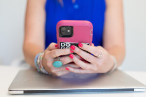 an unseen person holds a smart phone near a laptop