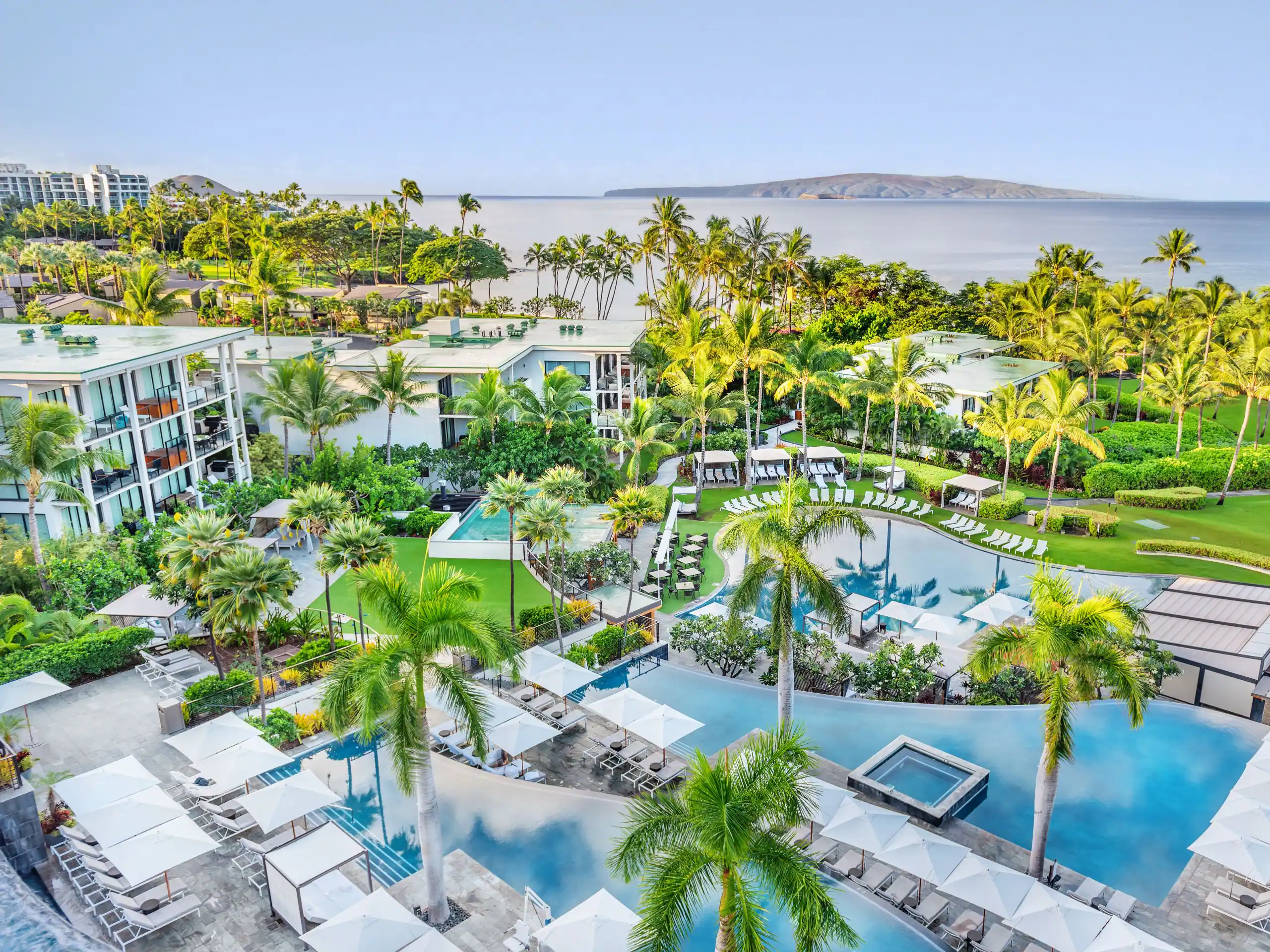 Hawaiian beachfront property showing multiple pools surrounded by palm trees, pools chairs, and cabanas